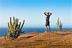 Man standing on mountain top, looking at view, rear view, Jericoacoara National Park, Ceara, Brazil