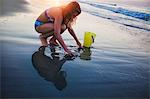 Girl drawing heart in sand on beach