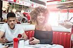 Young couple sitting in diner giving order to waitress