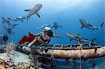 Underwater view of female free diver in bikini looking back at reef sharks, Bahamas