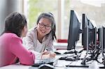 Smiling girl students researching at computer in laboratory classroom