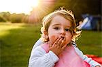 Portrait of female toddler eating breakfast with fingers on camping site