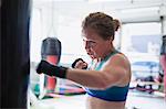 Determined female boxer boxing at punching bag in gym