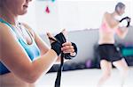 Female boxer wrapping wrist in gym