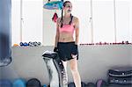 Confident young female boxer with padding in gym