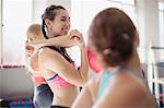 Smiling young woman stretching arm and shoulder in gym