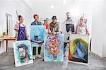 Portrait confident artists showing paintings in art class studio