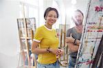 Portrait smiling artists painting at easel in art class studio