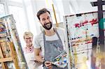 Portrait smiling artists painting at easels in art class studio