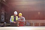 Male foreman and worker with clipboard talking in factory