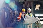 Engineers reviewing blueprints in steel factory