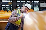 Focused male engineer with flashlight examining equipment in factory