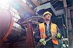 Confident male worker holding wrench in factory