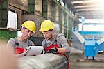 Male workers with clipboard in factory