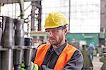 Focused male worker examining steel parts in factory