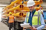Male foreman reading paperwork on clipboard in factory