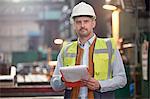 Portrait confident male foreman with clipboard in factory