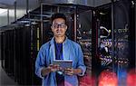 Portrait confident male IT technician with digital tablet in server room