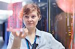 Female IT technician holding futuristic digital tablet in server room