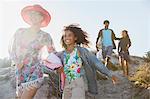 Smiling family walking on sunny summer beach hill