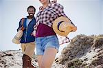 Smiling, enthusiastic couple walking on sunny summer sand beach path