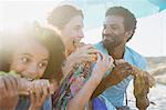 Happy family eating baguette sandwiches on sunny summer beach