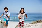 Playful brother and sister running on sunny summer ocean beach