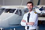 Portrait confident male pilot standing near airplane in hangar