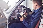 Male engineer checking diagnostics with digital tablet in airplane cockpit