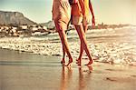 Barefoot young women walking on sunny summer ocean beach