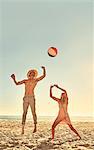 Young couple playing with beach ball on sunny summer beach