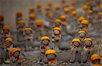 Close up of small brown Buddhist Jizo, Japanese stone statues, wearing orange hats, at Daienji, Tokyo, Japan.