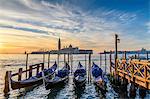 Gondolas moored on a canal in Venice, Italy, at sunrise.