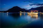Boat moored in harbour of Perast in the Bay of Kotor, Montenegro at night, mountain in the distance.