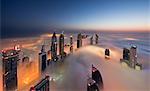 View of illuminated skyscrapers above the clouds in Dubai, United Arab Emirates at dusk.