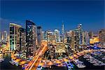 Cityscape of Dubai, United Arab Emirates at dusk, with illuminated skyscrapers and the marina in the foreground.