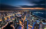 Cityscape of the Dubai, United Arab Emirates at dusk, with illuminated skyscrapers and coastline of the Persian Gulf.