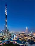 Cityscape of Dubai, United Arab Emirates at dusk, with illuminated Burj Khalifa skyscraper in the foreground.