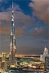 Cityscape of Dubai, United Arab Emirates, with illuminated Burj Khalifa skyscraper in the foreground.