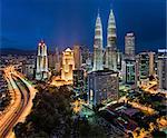 Cityscape of Kuala Lumpur, Malaysia at dusk, with illuminated Petronas Towers.