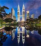 Illuminated Petronas Towers building in Kuala Lumpur, Malaysia at dusk. Reflection in lake.