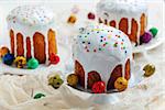 Easter cakes in glaze and dyed eggs on a white wooden table, selective focus.