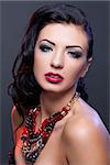 Beautiful brunette young woman with bright make-up and red lips wearing necklace. Copy space.