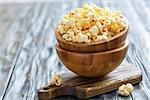 Bowls with salty popcorn on a wooden board, selective focus.