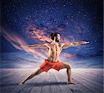 Man in a yoga position under the sky with stars