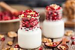 Fresh plain yogurt with pomegranate seeds and walnut in a glass jars for breakfast