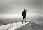 Businessman looks at the city from the roof above the city