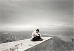 Alone desperate businessman sits on a roof. solitude and failure concept