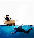 Fearful Businessman on cardboard while businessman with fin shark swims under water