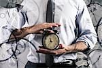 Businessman holds an alarm clock. Concept of delay and time